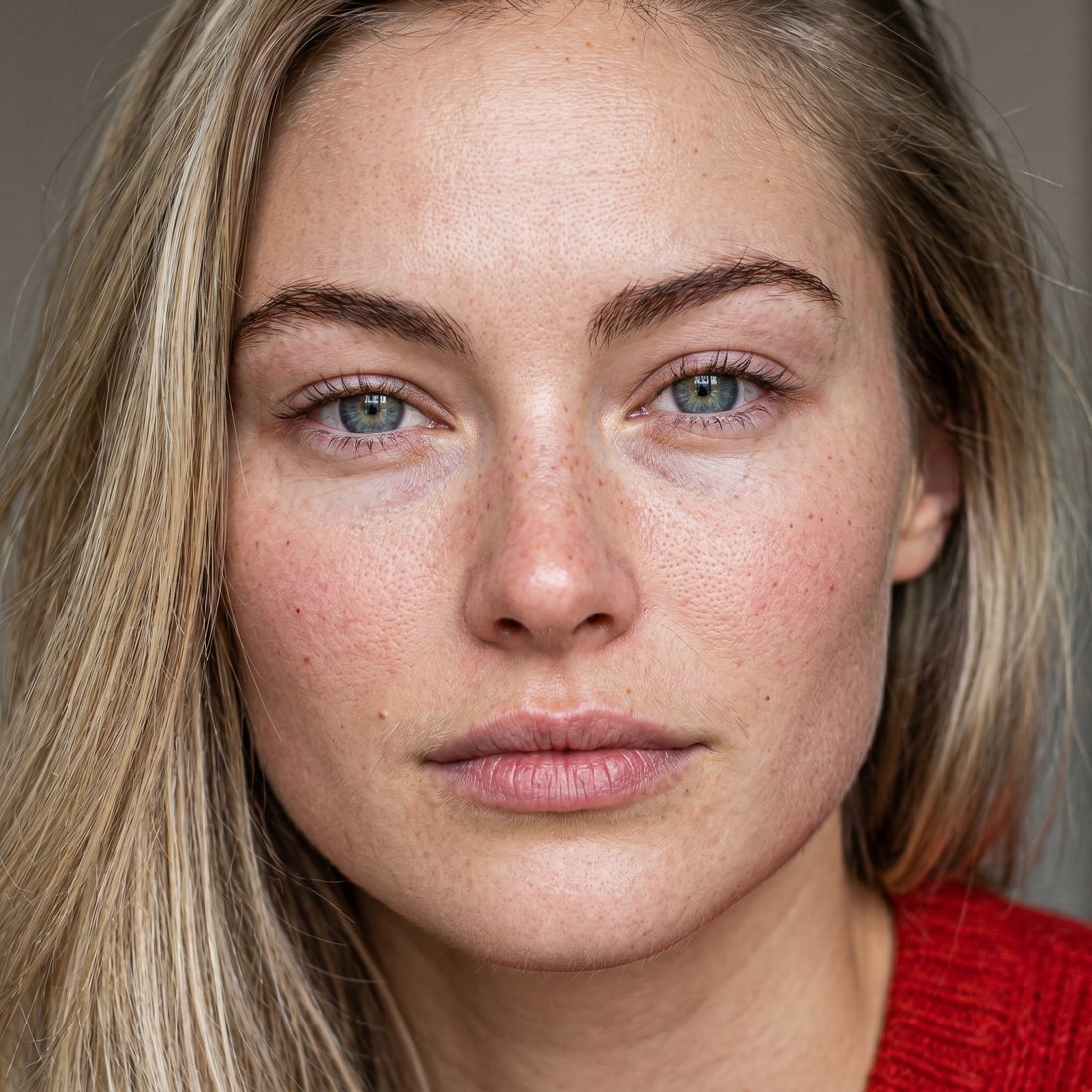 Same portrait after the skill — visible pores, natural flushing, sensor grain, real window light